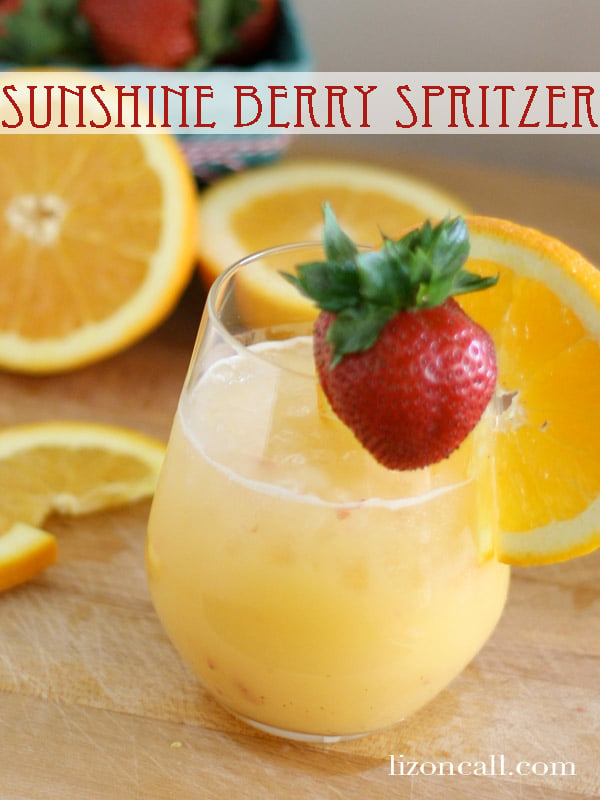 titled image - Sunshine Berry Spritzer - shown: a glass of brunch party punch garnished with a fresh strawberry on the rim