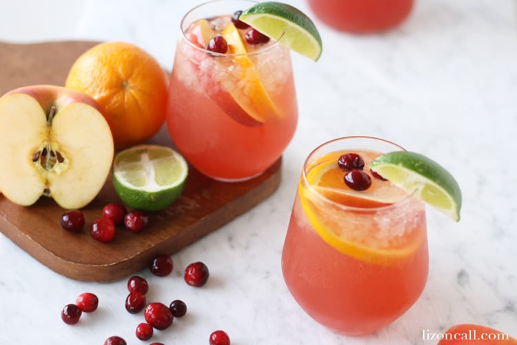 glasses of festive holiday party punch garnished with fresh fruit